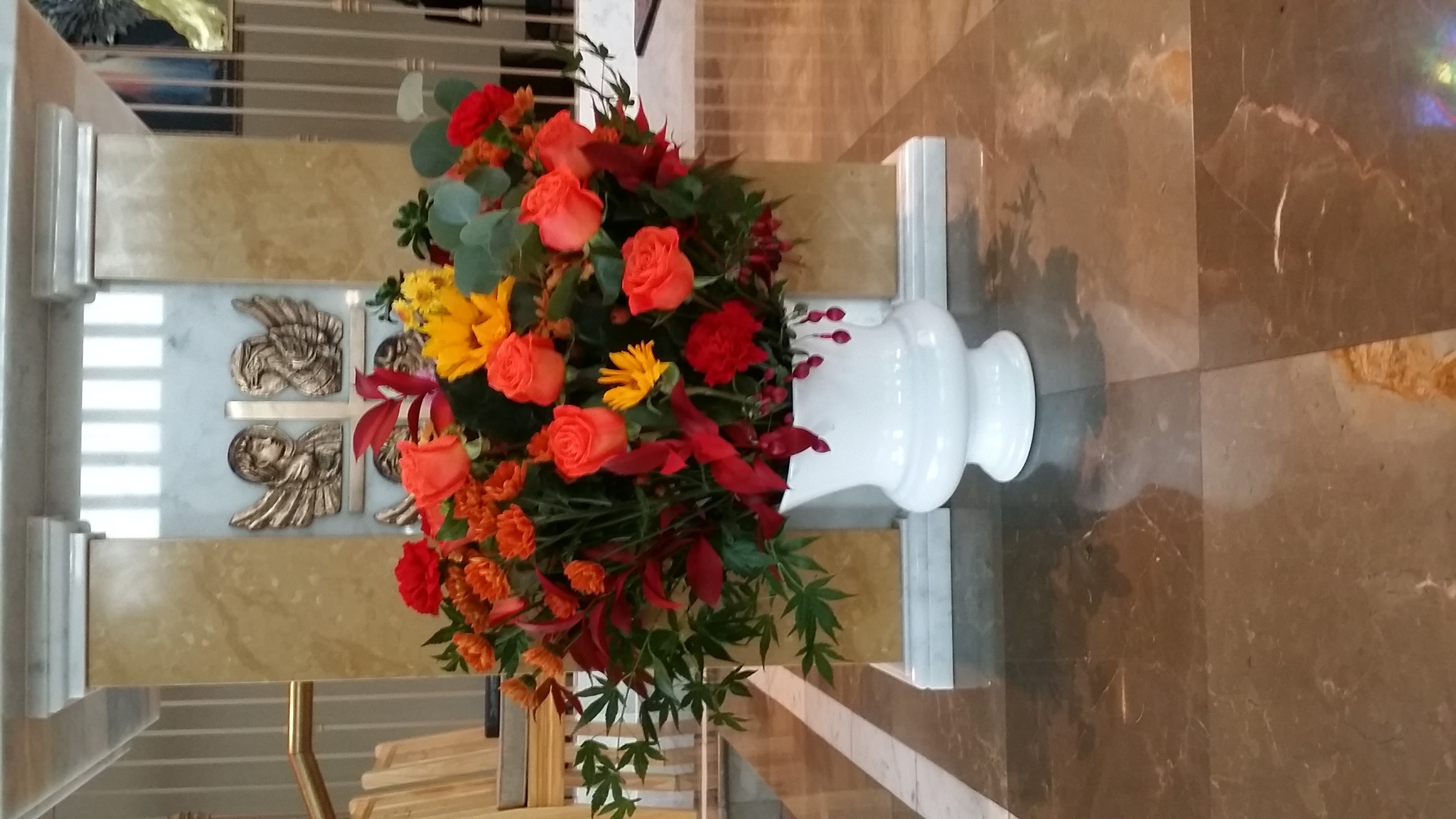 Coral-Orange Roses, Red Carnations, Burnt Orange Chrysanthemums, Yellow Sunflowers, Yellow Spray Chrysanthemums, Purple Liatris, Red Fuchsia, Eucalyptus, Red-tinted Ruscus, & Red & Green Japanese Maple
